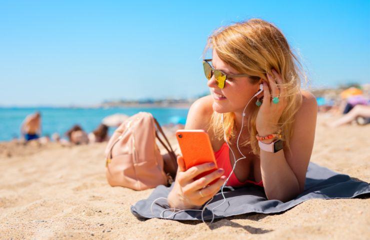 Ragazza ascolta musica in spiaggia